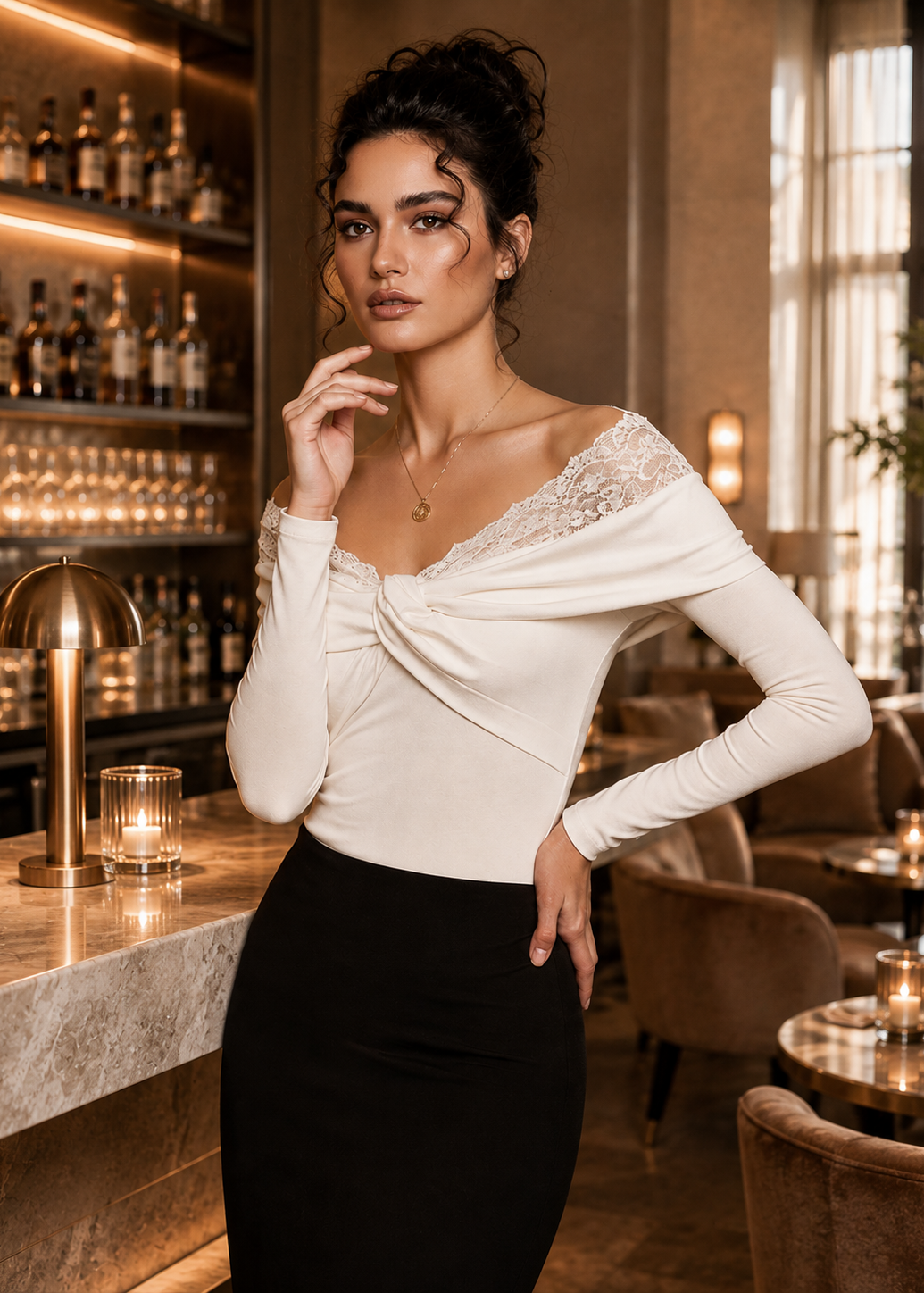 A woman posing in a warm, upscale bar or lounge setting, wearing a cream off-the-shoulder long-sleeve top with lace detailing and a black skirt.